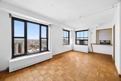 a view of an empty room with a window and wooden floor