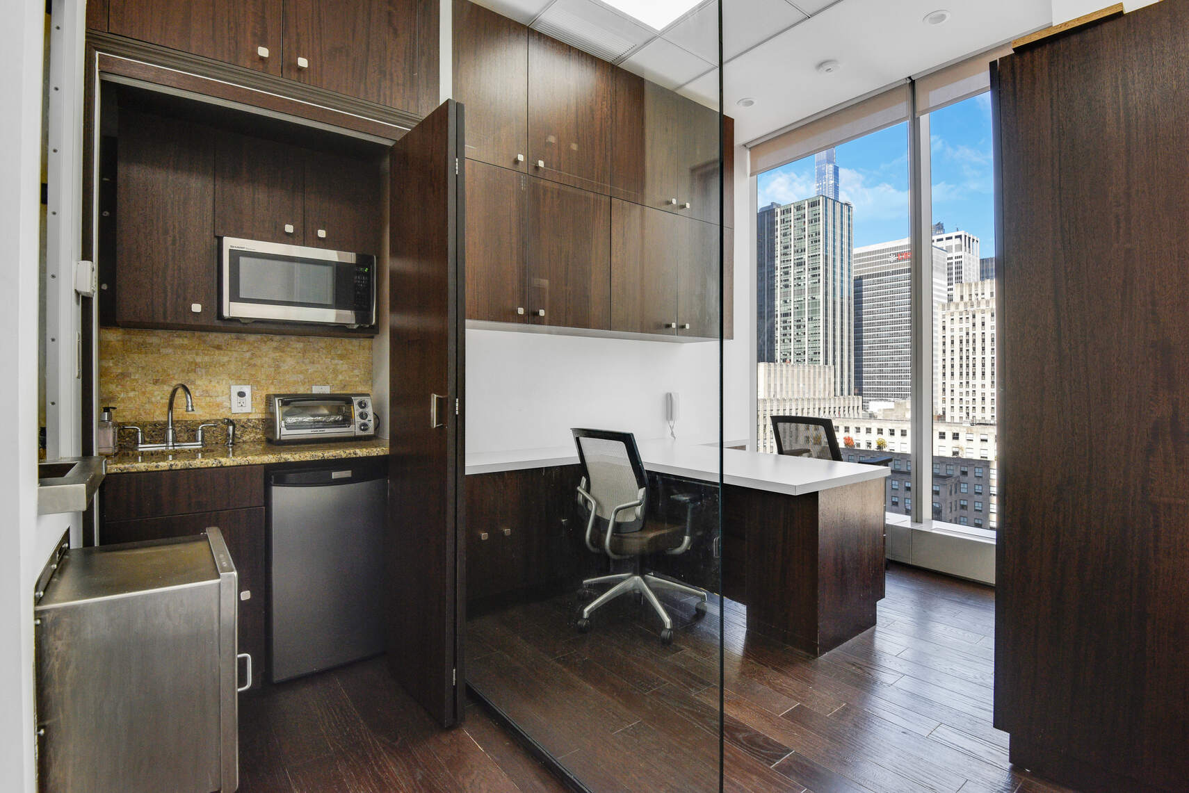 50 West 47th Street, Unit Undisclosed Manhattan, NY 10036 - Photo 7 of 27 a kitchen with a table chairs refrigerator and cabinets