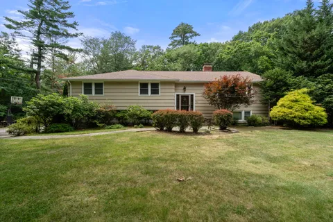 a front view of house with yard and trees in the background