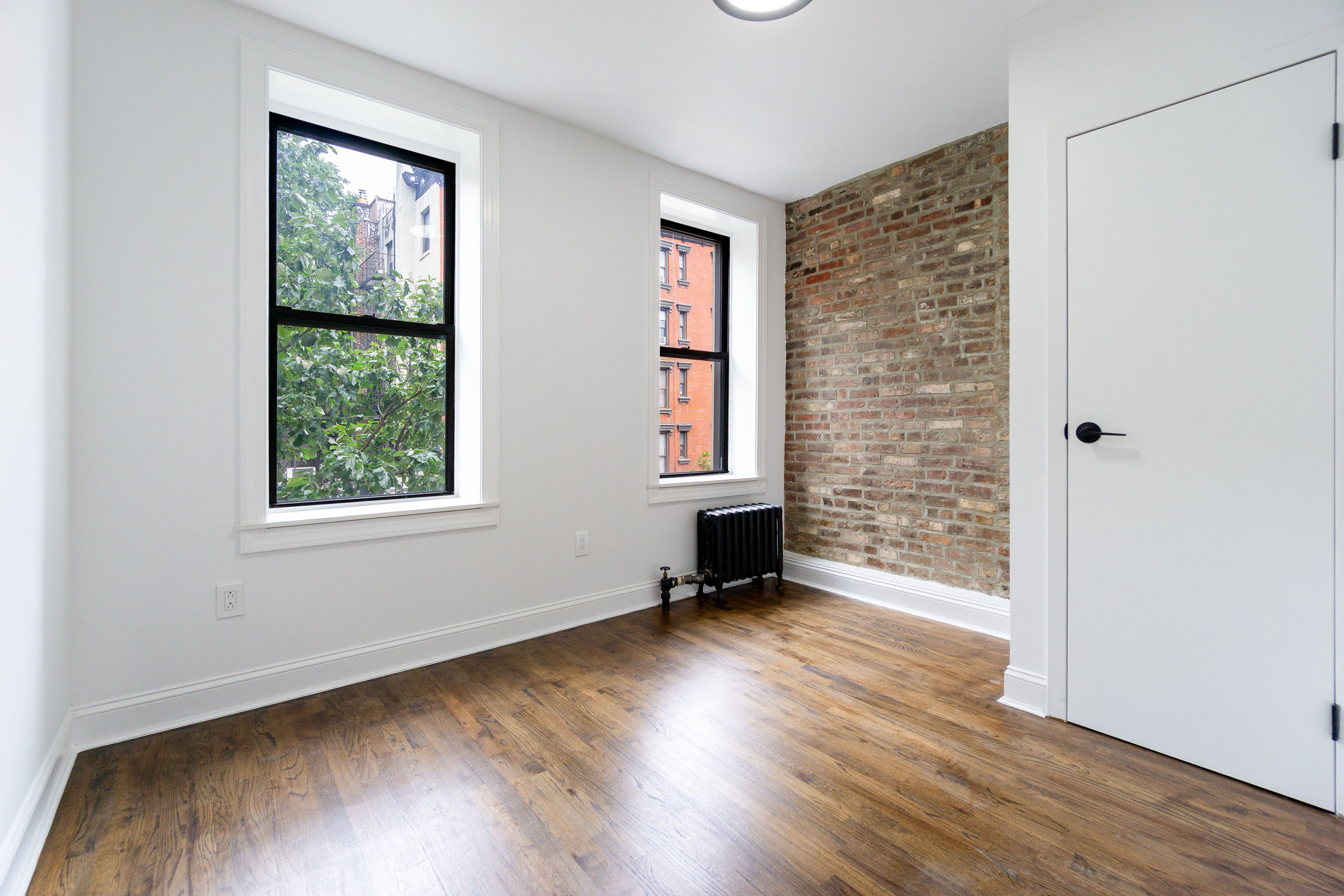 342 East 6th Street, Unit 3 Manhattan, NY 10003 - Photo 6 of 13 an empty room with wooden floor and windows