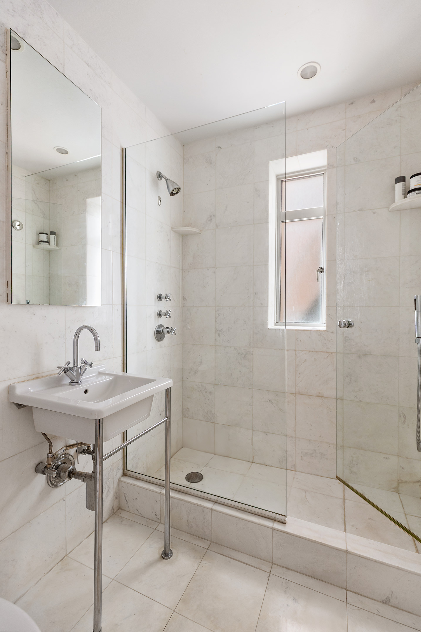 165 West 20th Street, Unit 4K Manhattan, NY 10011 - Photo 5 of 7 a bathroom with a sink mirror and a shower
