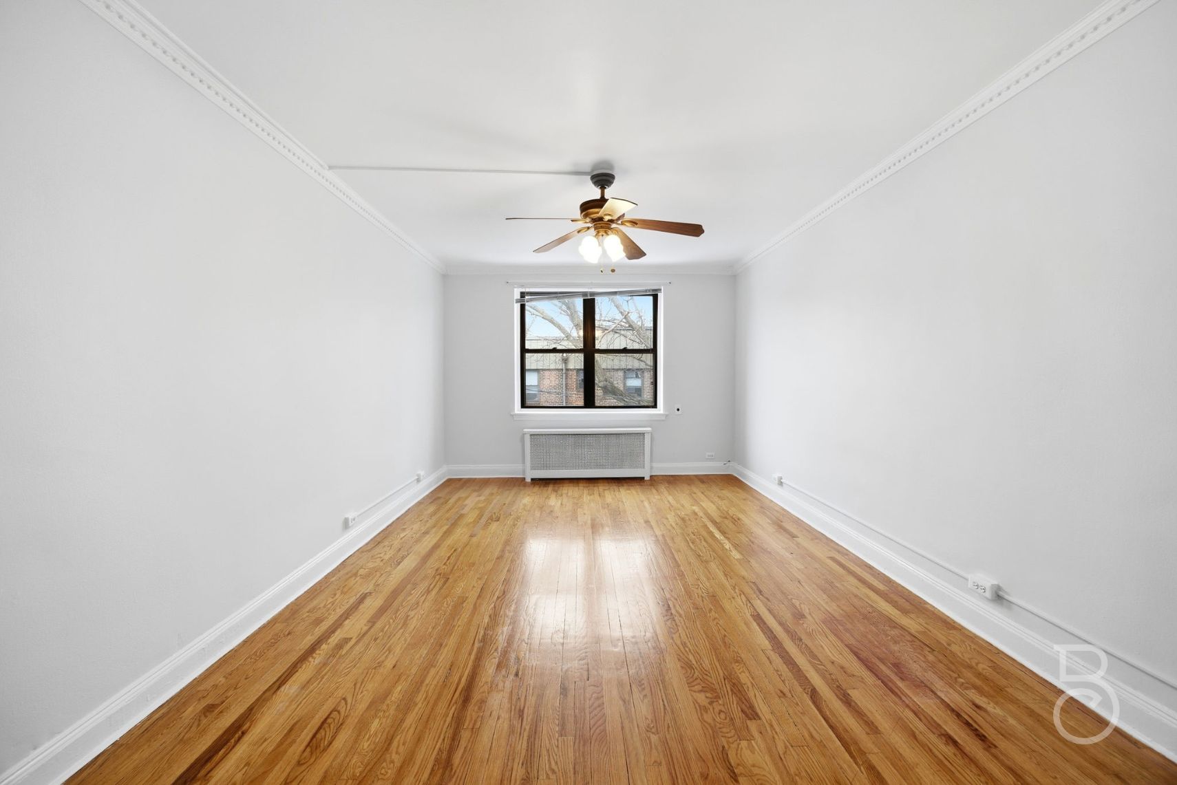78-15 19th Drive, Unit B2 Queens, NY 11370 - Photo 12 of 17 an empty room with wooden floor chandelier fan and windows