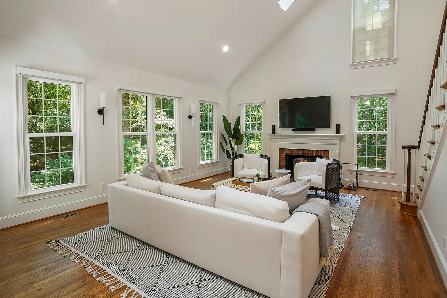 a living room with furniture a fireplace a flat screen tv and a large window