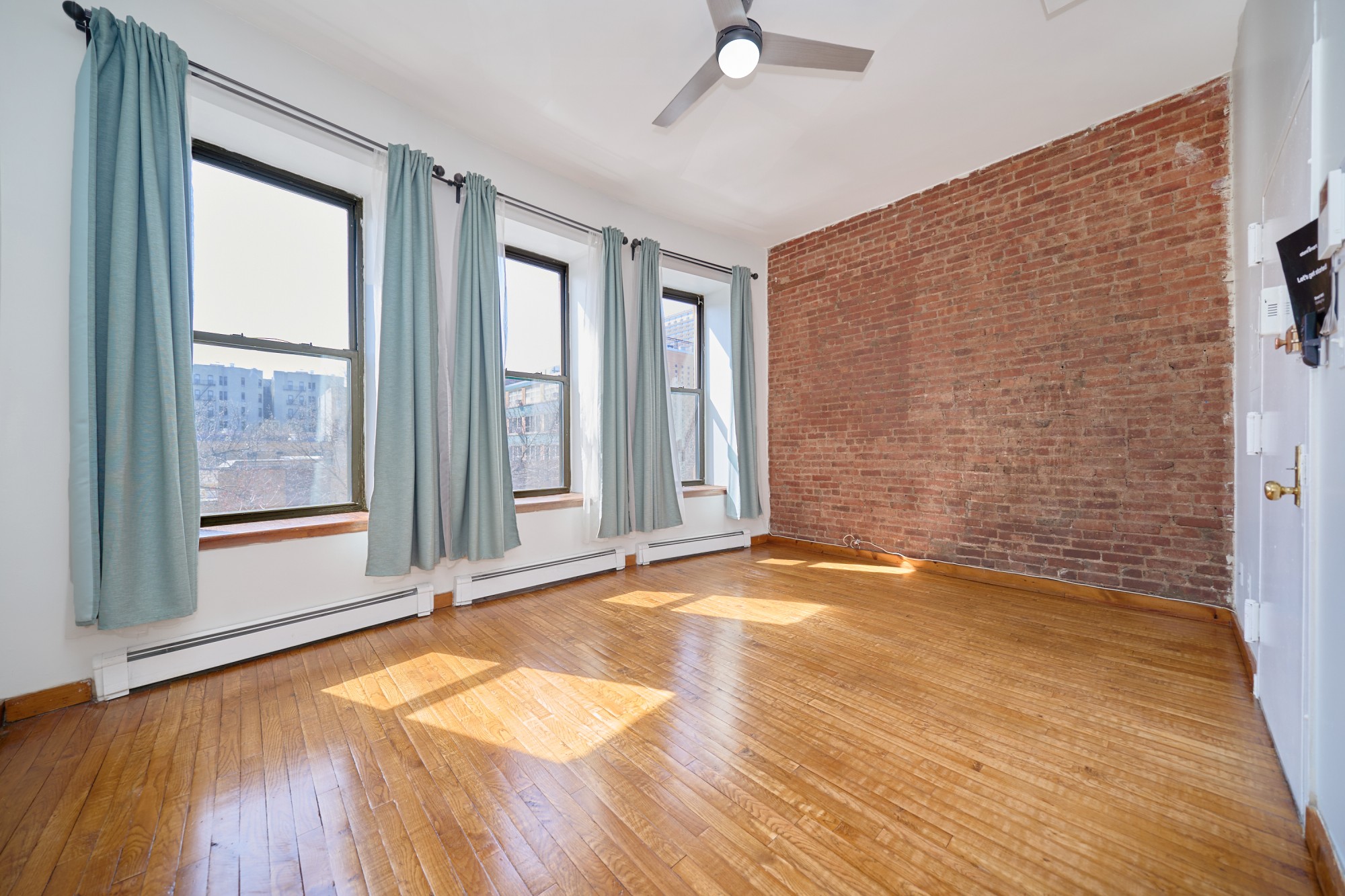 357 West 120th Street, Unit 2F Manhattan, NY 10027 - Photo 4 of 8 a view of an empty room with a window and wooden floor