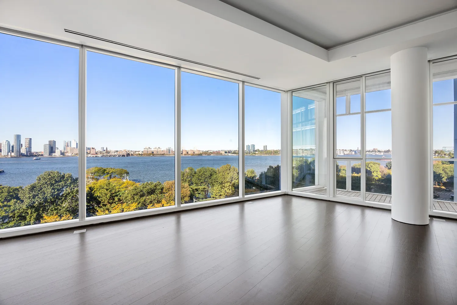 a view of an empty room with wooden floor and windows