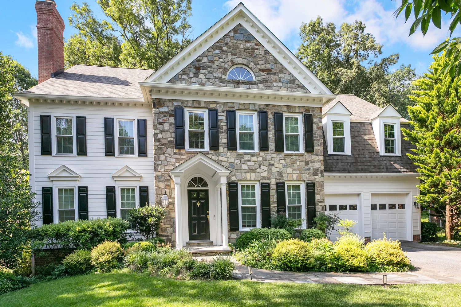 a view of a white house with large windows and a yard table and chairs