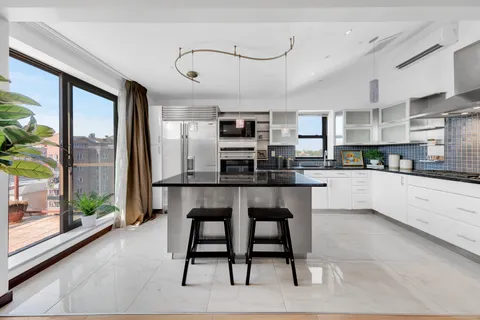 a kitchen with kitchen island a dining table chairs and white cabinets