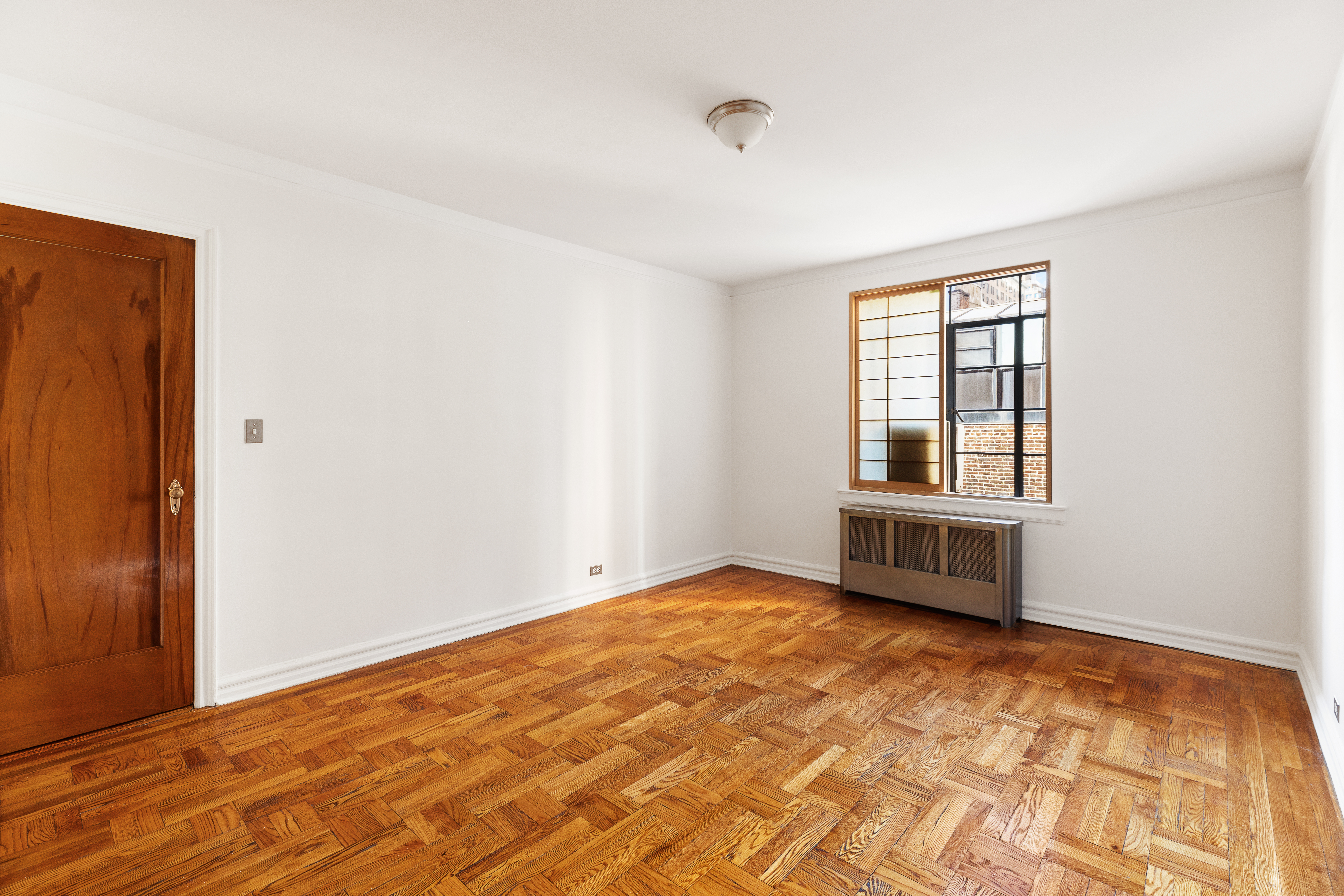 135 East 39th Street, Unit 5E Manhattan, NY 10016 - Photo 5 of 13 a view of an empty room with wooden floor and a window