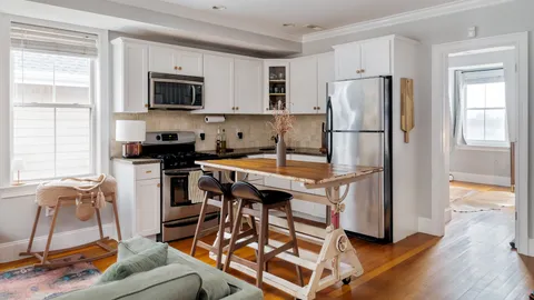 a kitchen with stainless steel appliances granite countertop a stove a refrigerator a sink a stove and white cabinets with wooden floor