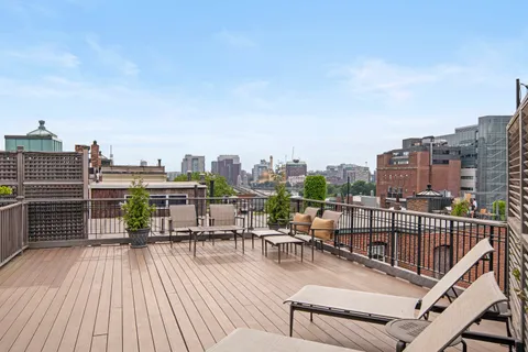 a view of a rooftop deck with chairs and wooden floor