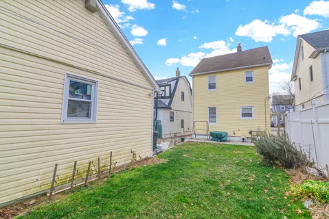 a backyard of a white house with potted plants and a chair