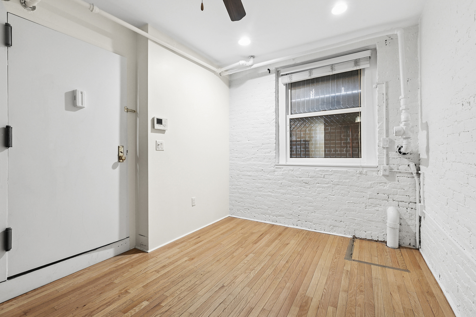 140 West 10th Street, Unit BTE Manhattan, NY 10014 - Photo 3 of 12 a view of an empty room with wooden floor and a window