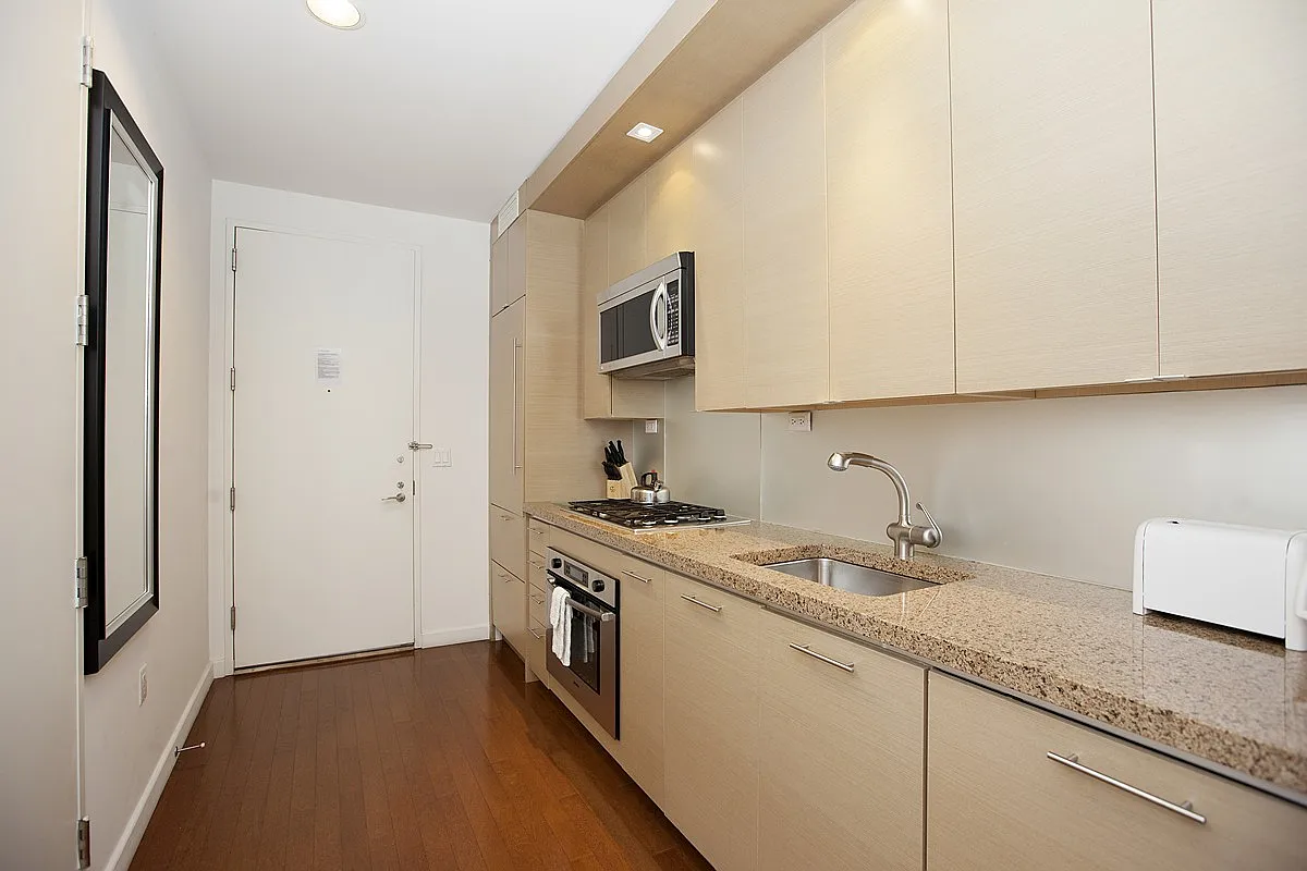 1600 Broadway, Unit 7F Manhattan, NY 10019 - Photo 4 of 7 a kitchen with granite countertop a sink stove and cabinets