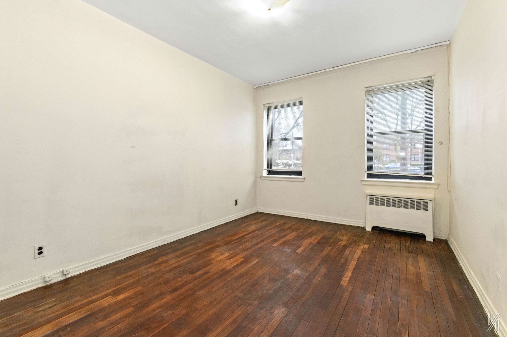 22-60 79th Street, Unit 1A Queens, NY 11370 - Photo 8 of 17 an empty room with wooden floor and windows