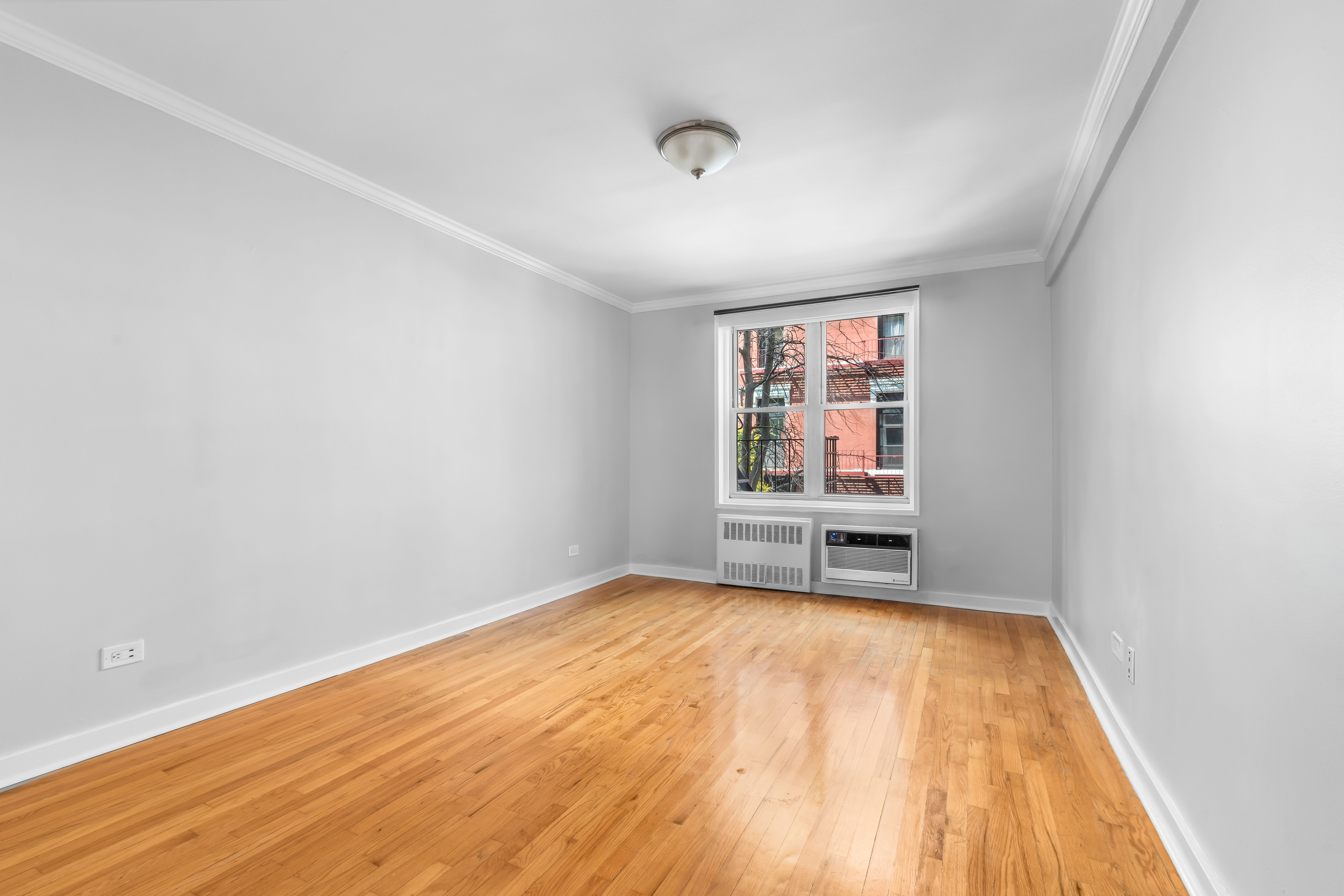 88 Bleecker Street, Unit 2M Manhattan, NY 10012 - Photo 8 of 14 an empty room with wooden floor closet and windows