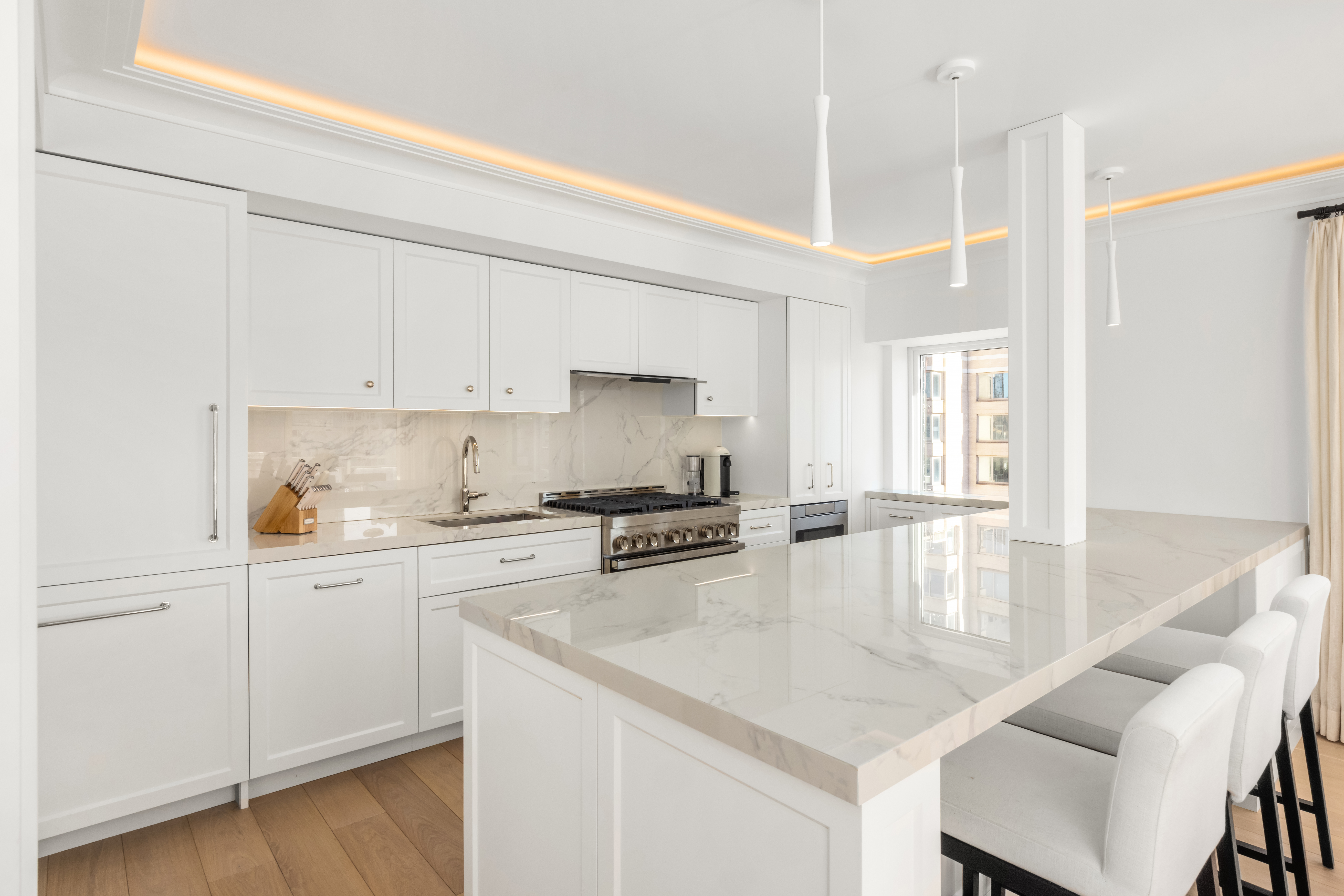 150 East 69th Street, Unit 18S Manhattan, NY 10021 - Photo 7 of 16 a kitchen with stainless steel appliances granite countertop a stove a sink and white cabinets with wooden floor