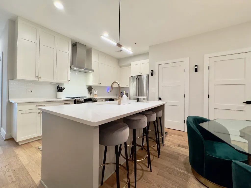 a kitchen with stainless steel appliances kitchen island a table chairs sink and cabinets