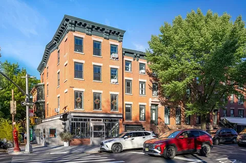 a front view of a building with lot of cars and trees