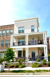 a front view of white house with lots of windows and plants