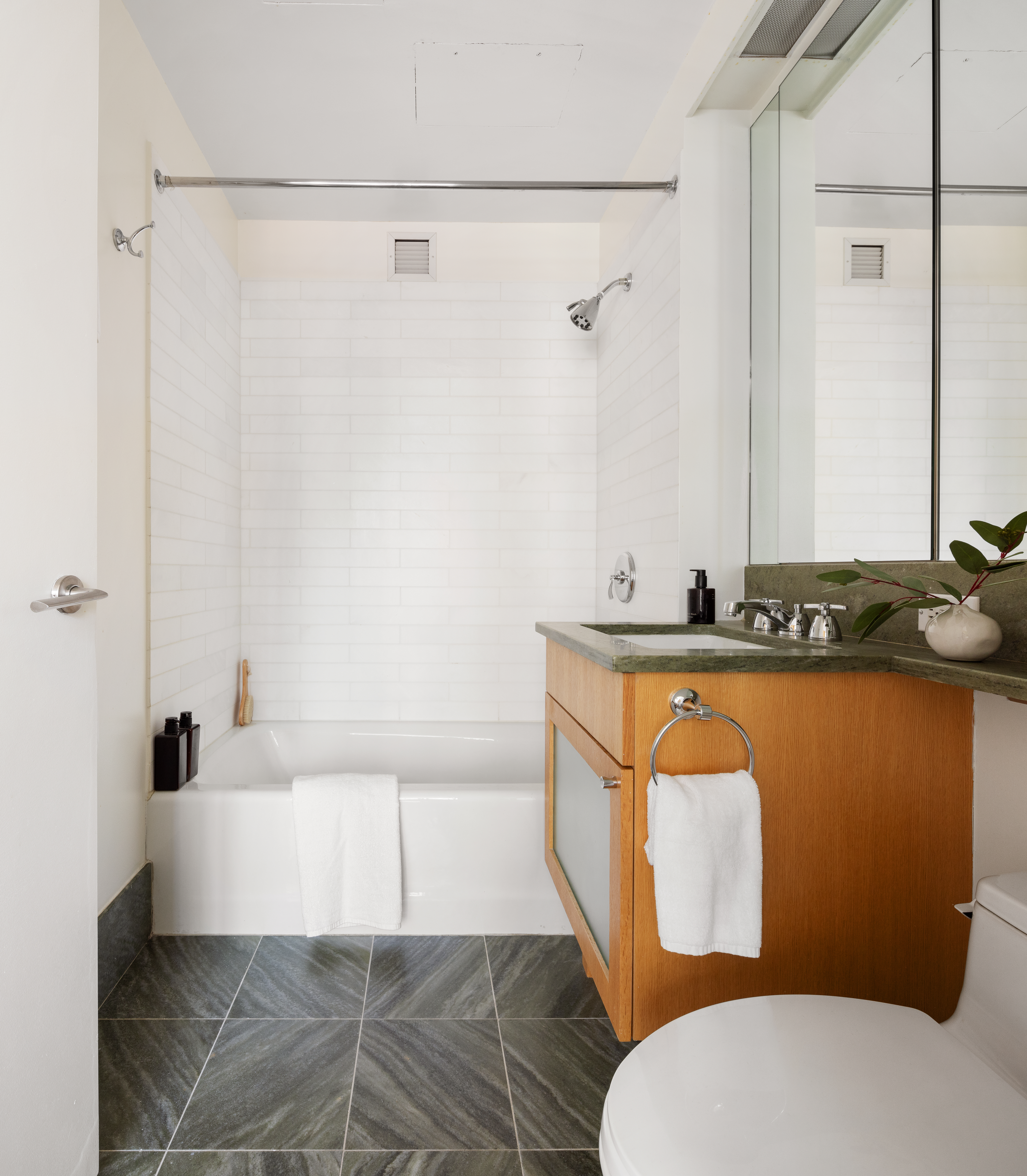 207 East 57th Street, Unit 18A Manhattan, NY 10022 - Photo 8 of 10 a bathroom with a granite countertop bathtub sink vanity mirror and toilet