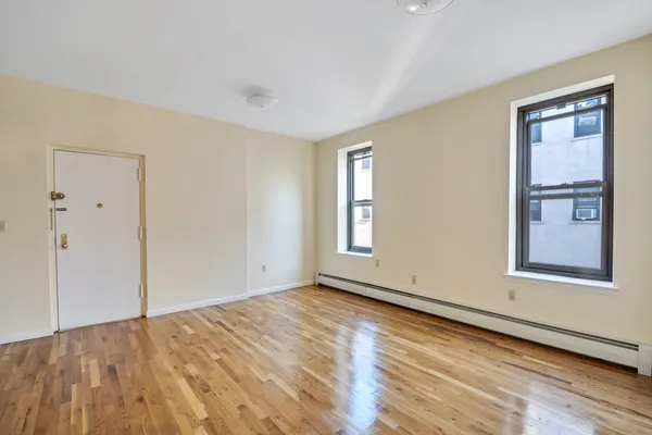 a view of an empty room with window and wooden floor