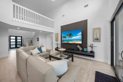 a living room with furniture a rug kitchen view and a chandelier