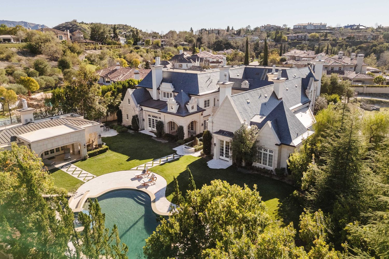 an aerial view of a house with a swimming pool a yard and mountain view in back