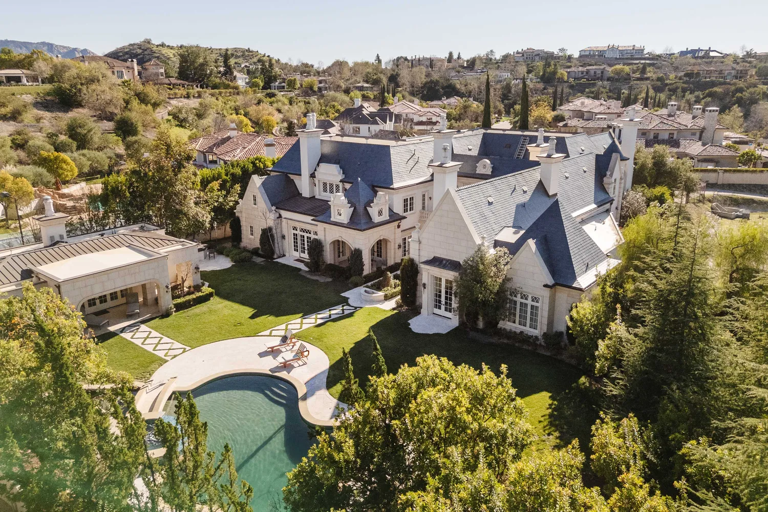 an aerial view of a house with a swimming pool a yard and mountain view in back