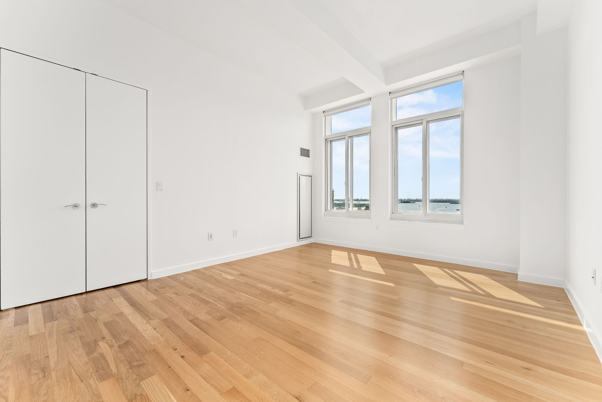 85 Adams Street, Unit 21A Brooklyn, NY 11201 - Photo 7 of 18 a view of an empty room with wooden floor and a window