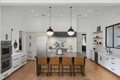 a kitchen with stainless steel appliances kitchen island granite countertop a table chairs sink and cabinets
