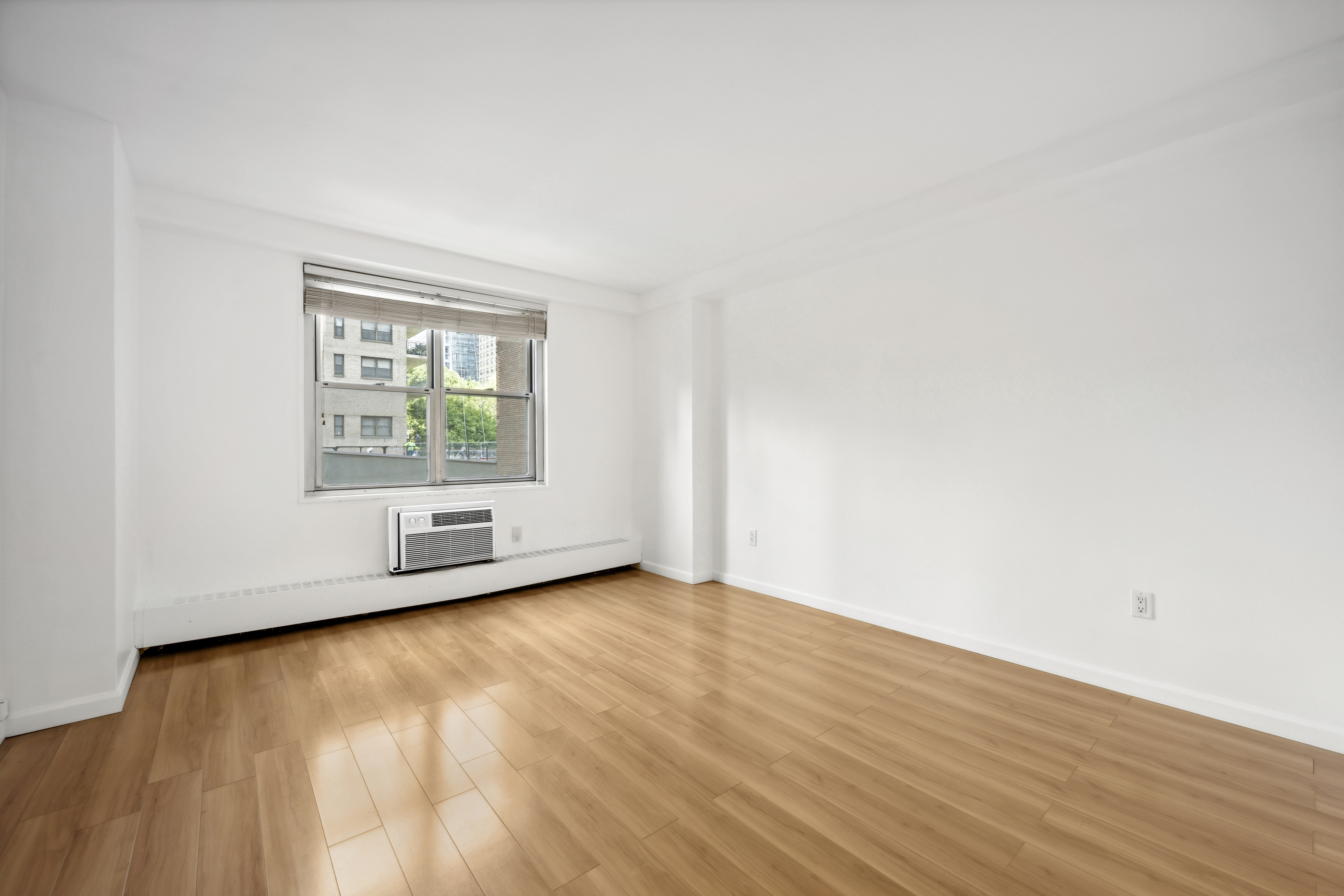 303 West 66th Street, Unit 2AE Manhattan, NY 10023 - Photo 6 of 15 an empty room with wooden floor and windows