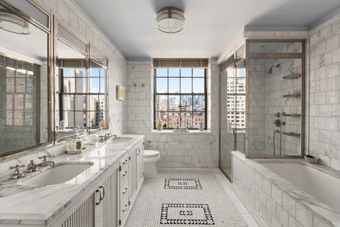 a spacious bathroom with double vanity sink a mirror a bathtub and next to a window