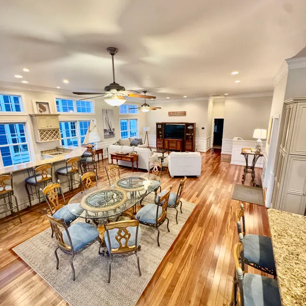 a living room with furniture kitchen view and a wooden floor