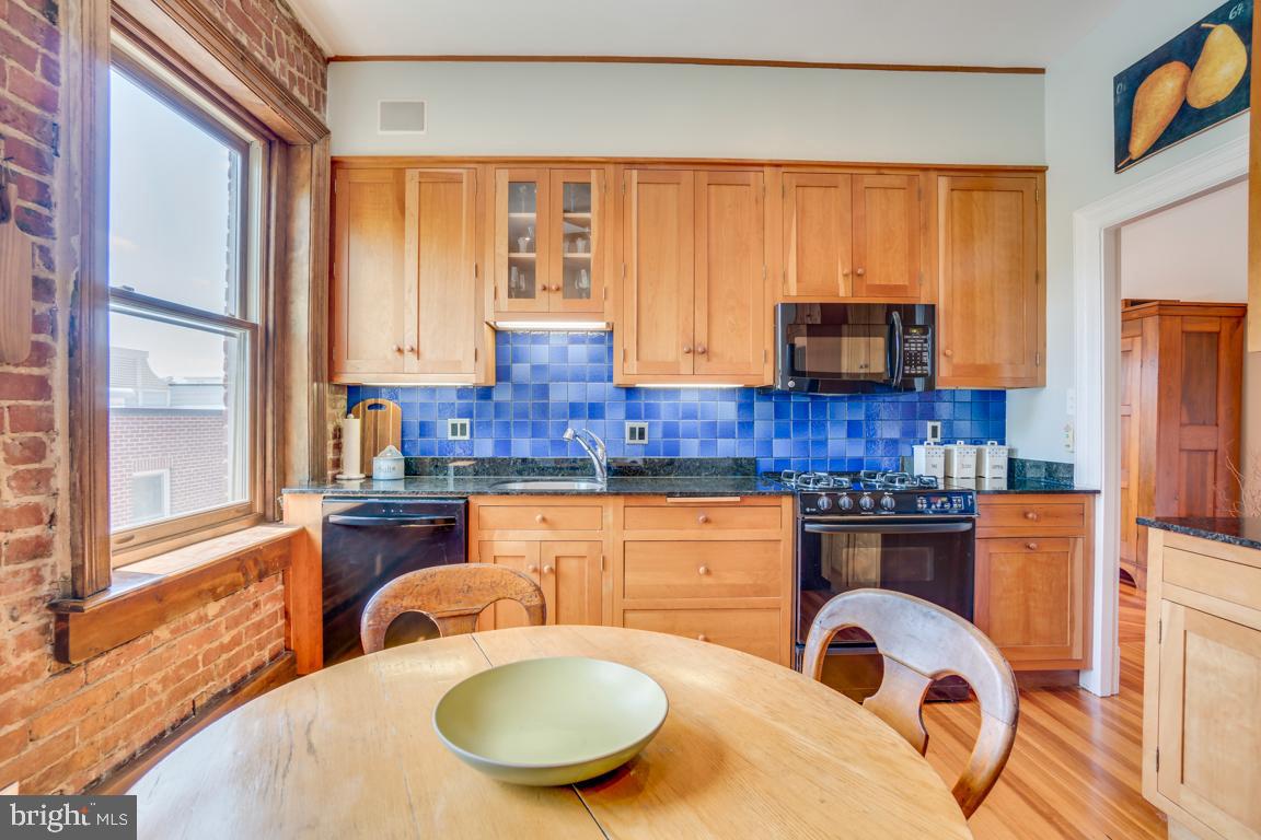 2415 20th Street Northwest, Unit 38 Washington, DC 20009 - Photo 12 of 30 a kitchen with stainless steel appliances granite countertop a stove a sink a microwave and wooden cabinets