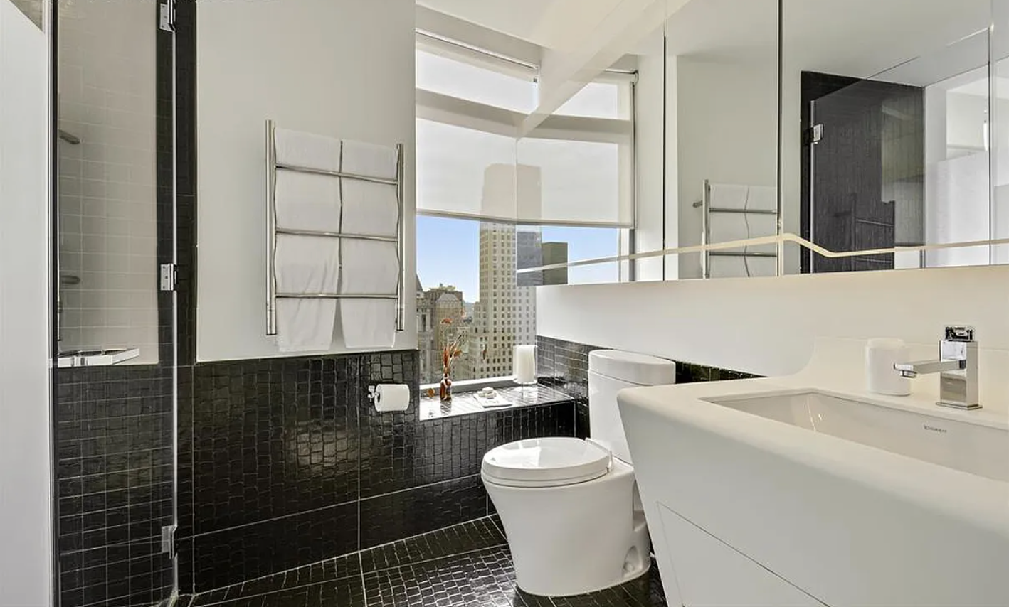 123 Washington Street, Unit 43F Manhattan, NY 10006 - Photo 4 of 8 a bathroom with a sink a toilet and a mirror