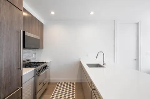 a kitchen with a sink and a stove top oven with wooden floor