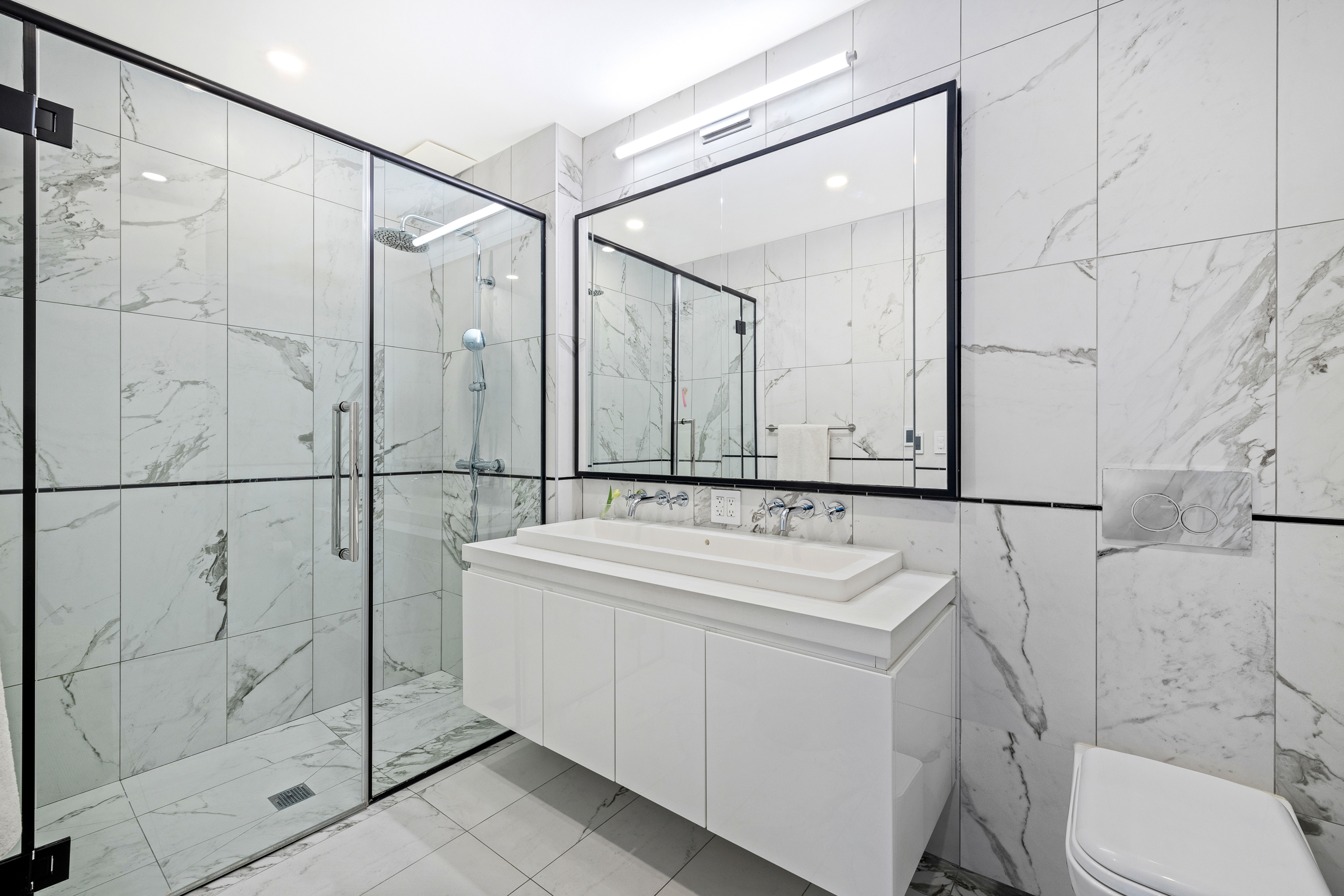 427 East 90th Street, Unit 5A Manhattan, NY 10128 - Photo 6 of 13 a bathroom with a sink toilet vanity and shower