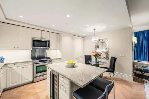 a kitchen with stainless steel appliances granite countertop a stove top oven a sink dishwasher and a refrigerator with wooden floor