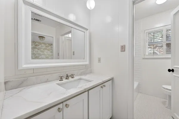 a bathroom with a granite countertop sink a toilet and a mirror