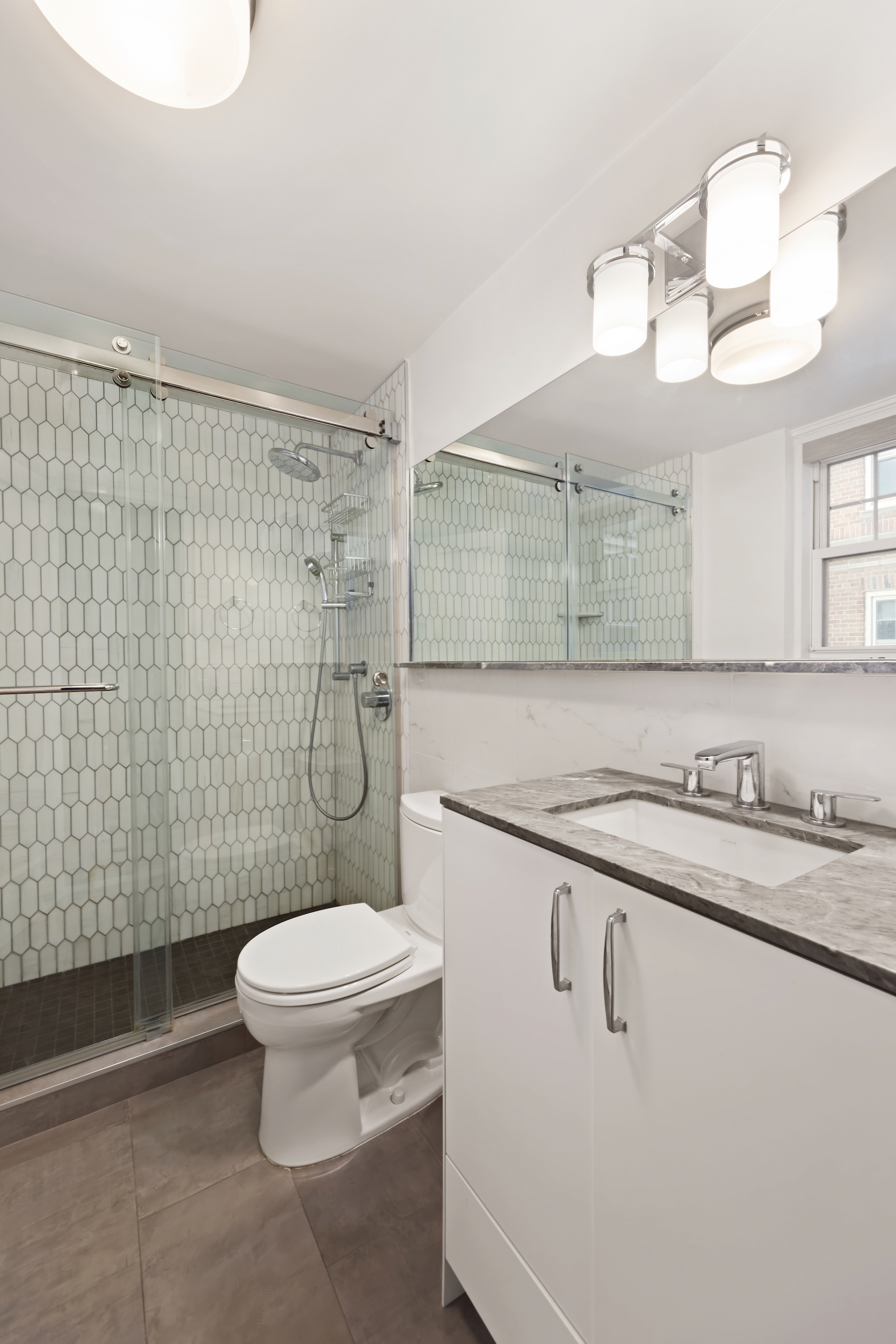 160 Cabrini Boulevard, Unit 22 Manhattan, NY 10033 - Photo 8 of 23 a bathroom with a granite countertop sink a toilet a mirror and shower