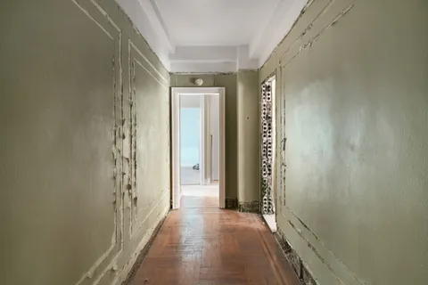 a view of a hallway with wooden floor and closet