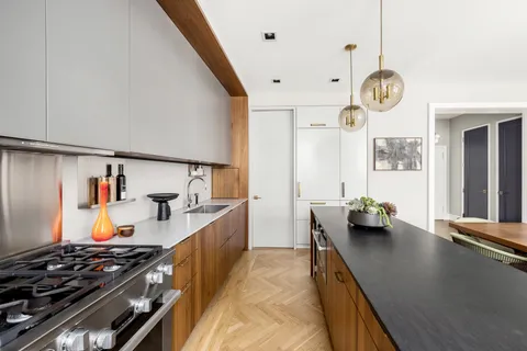 a kitchen with stainless steel appliances granite countertop a stove a sink a refrigerator and a wooden floors