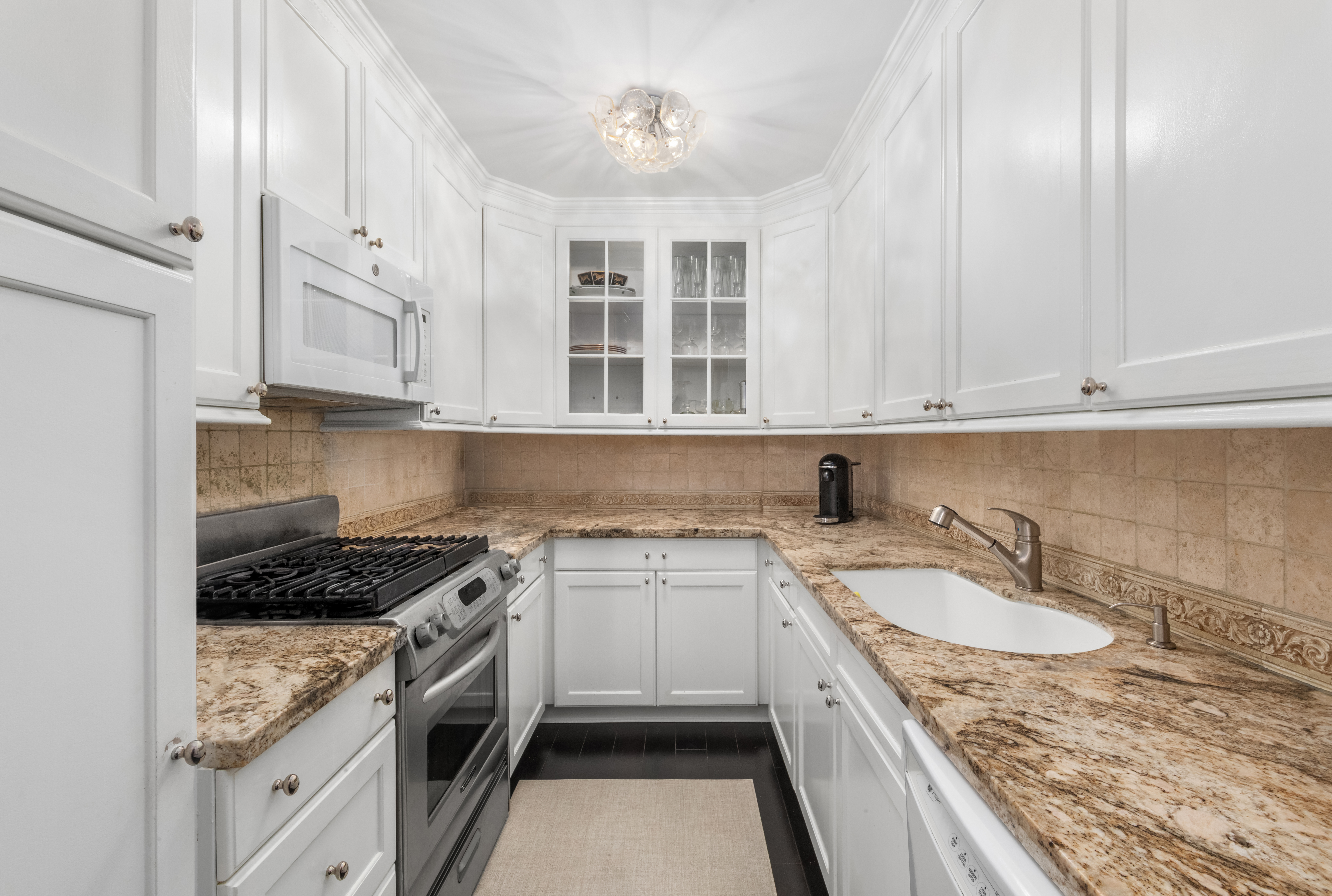27 East 65th Street, Unit 10BC Manhattan, NY 10065 - Photo 10 of 16 a kitchen with stainless steel appliances granite countertop a sink stove and cabinets