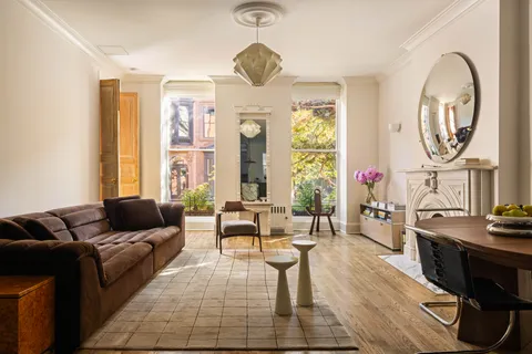 a living room with furniture and a large mirror next to a window