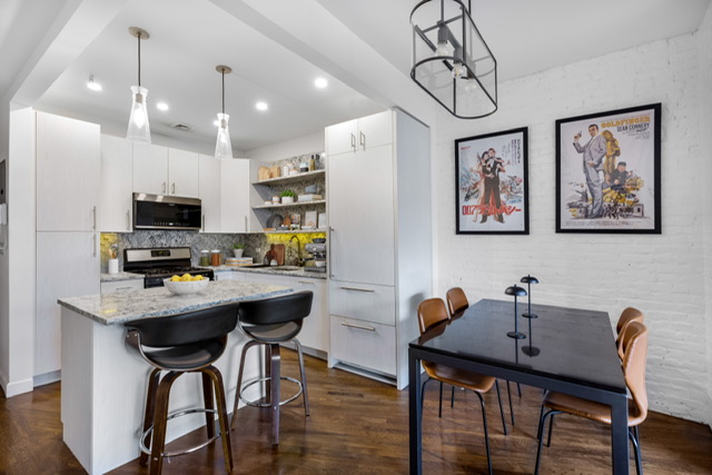 161 Remsen Street, Unit 2C Brooklyn, NY 11242 - Photo 3 of 13 a kitchen with stainless steel appliances kitchen island a table and chairs in it