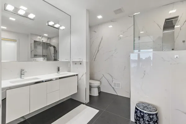 a bathroom with a double vanity sink a toilet and a shower