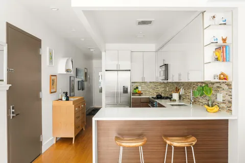 a kitchen with stainless steel appliances a dining table chairs and wooden floor