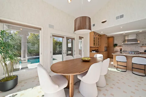 a dining hall with stainless steel appliances kitchen island granite countertop a table chairs in it and a large window