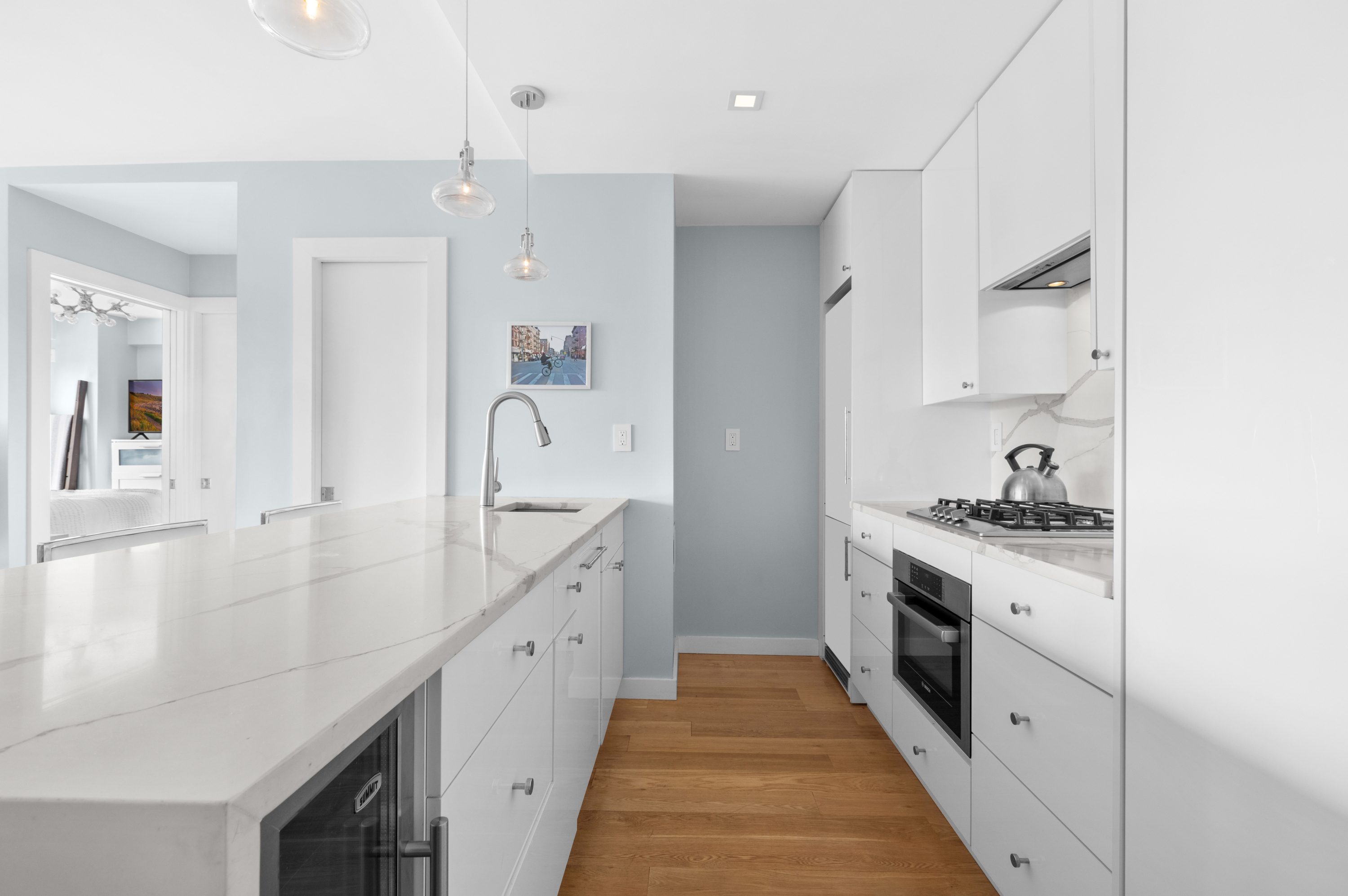 201 West 21st Street, Unit 15J Manhattan, NY 10011 - Photo 3 of 6 a large white kitchen with stainless steel appliances a sink stove and cabinets