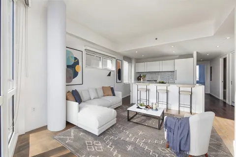 a living room with furniture white walls and kitchen view